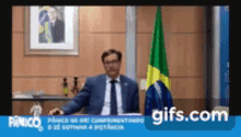 a man in a suit and tie is sitting in front of a flag ..