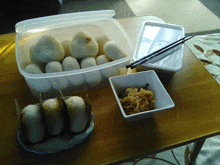 a plastic container filled with rice balls next to a bowl of food