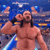 a shirtless wrestler is standing in front of a sign that says allegiance stadium