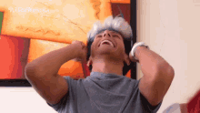 a man wearing headphones is laughing in front of a painting that says " colombia.com "