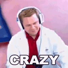 a man wearing headphones and a lab coat is sitting on a pink surface .