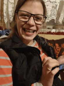 a woman wearing glasses is smiling while holding a cellphone