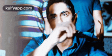 a man in a blue shirt is covering his face with his hand and the words kulfyapp.com are visible in the corner