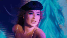 a woman wearing a black beret and blue eye shadow is dancing in a dark room .