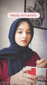 a woman in a hijab holds a kfc cup in her hand