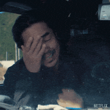 a man is covering his face in a car with a netflix logo in the background
