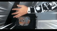 a person wearing a white watch is reaching into a box