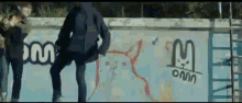 a skateboarder is standing in front of a wall with graffiti on it that says omni