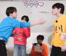 a group of young men are standing in a room and one of them is wearing a yellow sweater with the letter i on it