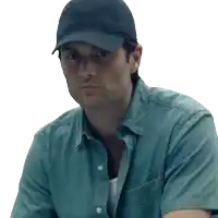 a man wearing a hat and a blue shirt is looking at the camera