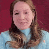 a woman with long hair is wearing a blue sweater and earrings and making a funny face .