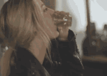 a woman is drinking a glass of wine from a glass .