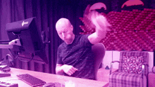 a bald man is sitting at a desk in front of a computer monitor that says ' gigabyte ' on it
