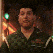 a man in a green checkered shirt is standing in front of a green traffic light .