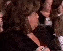 a woman is sitting in a crowd of people at a concert and talking to another woman .