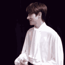 a young man is wearing a white shirt with ruffles on the sleeves and collar .