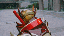 a red and gold object with spikes on it is on a brick sidewalk