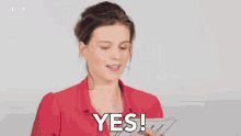 a woman is holding a piece of paper and saying yes .