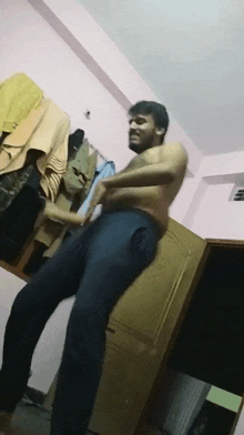 a man without a shirt is dancing in a room with clothes hanging on the wall