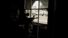 a man with a rifle looking out a window