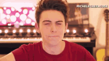 a young man in a red shirt is making a funny face .