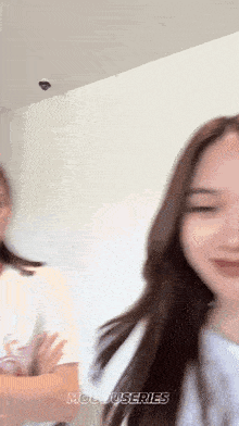 two women are standing next to each other and one of them is wearing a white shirt and the other is wearing a black shirt .