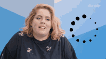 a woman is smiling in front of a blue wall with the elite daily logo