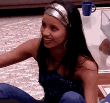 a woman wearing a headband is sitting on the floor smiling