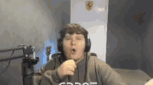 a man wearing headphones and a hoodie is sitting in front of a microphone .