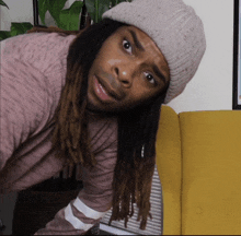 a man with dreadlocks wearing a pink shirt and a white hat