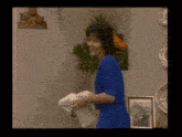 a woman in a blue shirt is standing in front of a planter of flowers .