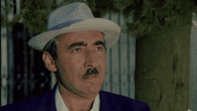 a man with a mustache wearing a hat and suit