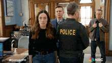 a group of people standing in a room with a police officer in the foreground