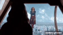 a woman in a supergirl costume is flying over a city ..