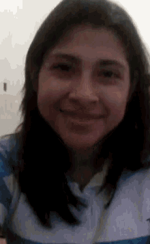 a woman in a blue and white shirt is smiling for the camera