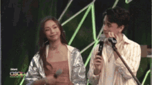 a man is holding a microphone while a woman stands behind him