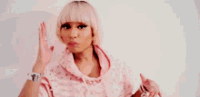 a woman is wearing a pink hoodie and making a peace sign .