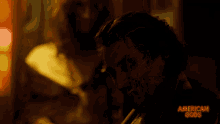 a man is smiling in a dark room with the words american gods on the bottom