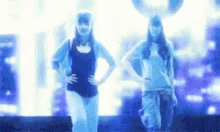 two women are standing next to each other with their hands on their hips in front of a blue background .