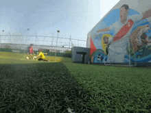 two soccer players on a field with a mural on the wall behind them
