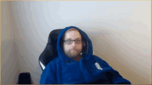 a man with glasses and a beard wearing a blue hoodie