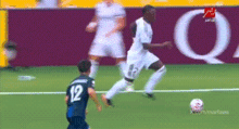 a soccer player wearing a number 12 jersey kicks the ball