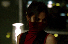 a woman wearing a red turtleneck covering her face in a dark room