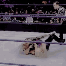 two women are wrestling in a wrestling ring with a referee watching