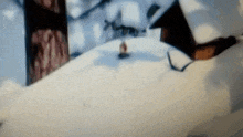 a blurred image of a snowy landscape with a few houses in the background