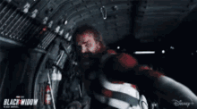 a man in a red and white striped suit is standing in a dark room .