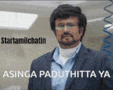 a man with glasses and a beard is standing in front of a sign that says startamilchatin