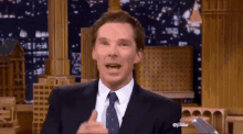 a man in a suit and tie is giving the thumbs up sign