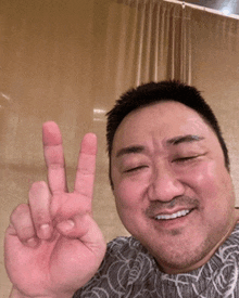 a man is smiling and giving the peace sign