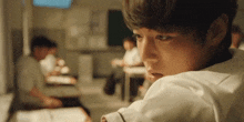 a young boy is sitting at a desk in a classroom looking over his shoulder .